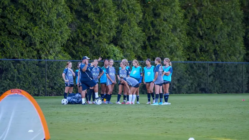 The U13 CCFC Girls Academy academy team huddled up around coach listening to instructions