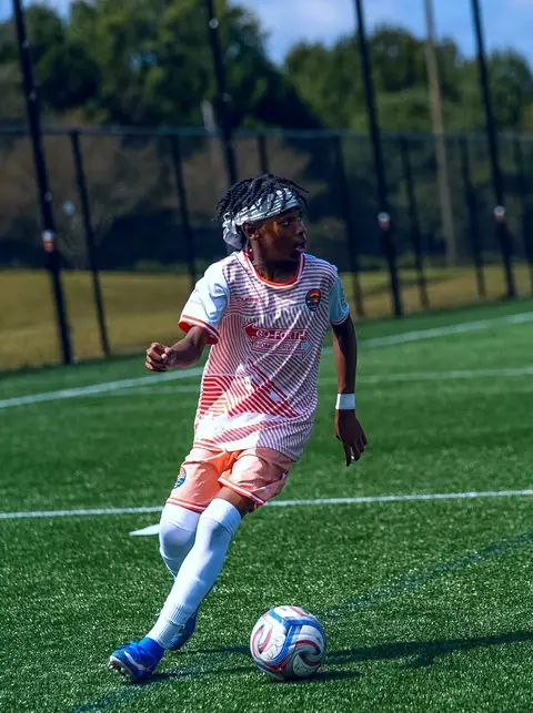 One U13 Homegrown player in an orange CCFC kit makes a turn with the ball at Phillips Park