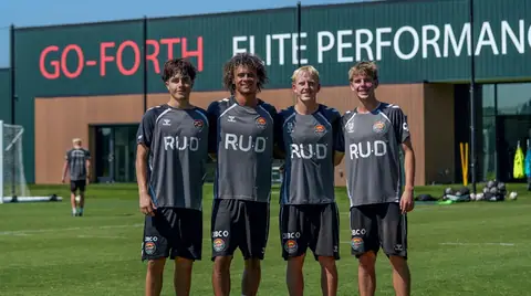 Four academy players in CCFC training kit standing together on the pitch outside the Go-Forth Elite Performance Center